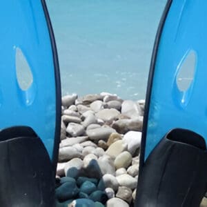 A pair of blue surfboards sitting on top of rocks.