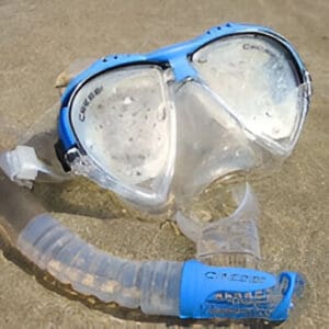A blue and white mask with a tube of water on the beach.