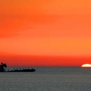 Sunset over the ocean with a ship.