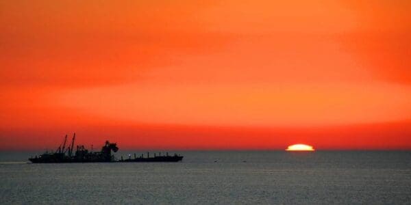 Sunset over the ocean with a ship.